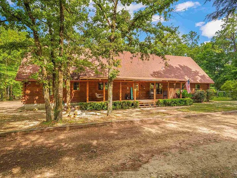 A log cabin lodge shaded by mature oaks on the ranch